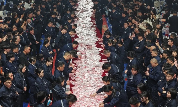 Nhân viên xếp hàng chờ đếm tiền nhận thưởng trong tiệc đại hội thường niên của công ty hôm 13/2. Ảnh: Sina