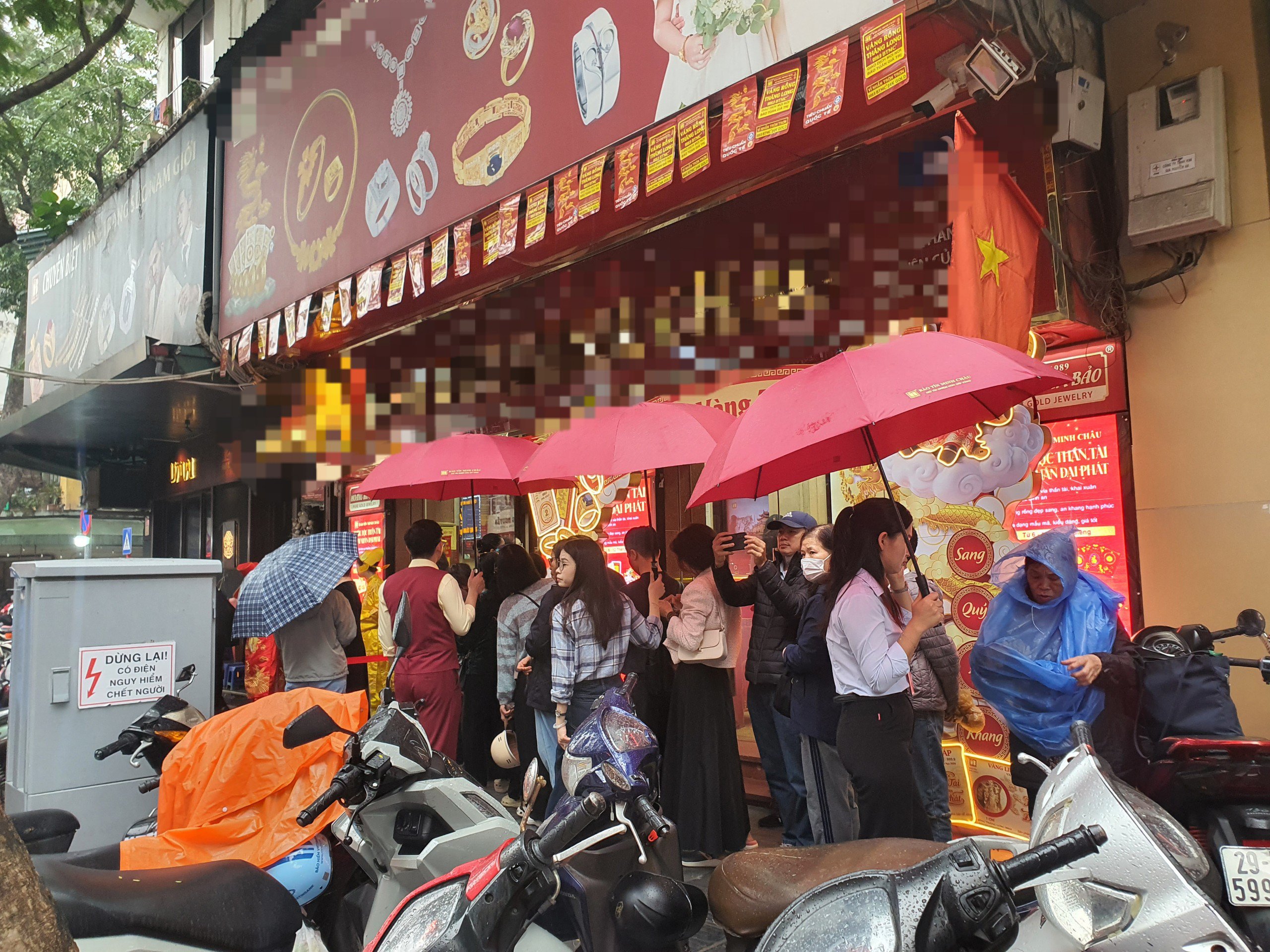 Mặc dù trời mưa nhưng khách phía cửa hàng này vẫn đứng xếp hàng, không có hiện tượng chen lấn, xô đẩy. Nhân viên thay nhau cầm ô che mưa cho khách.