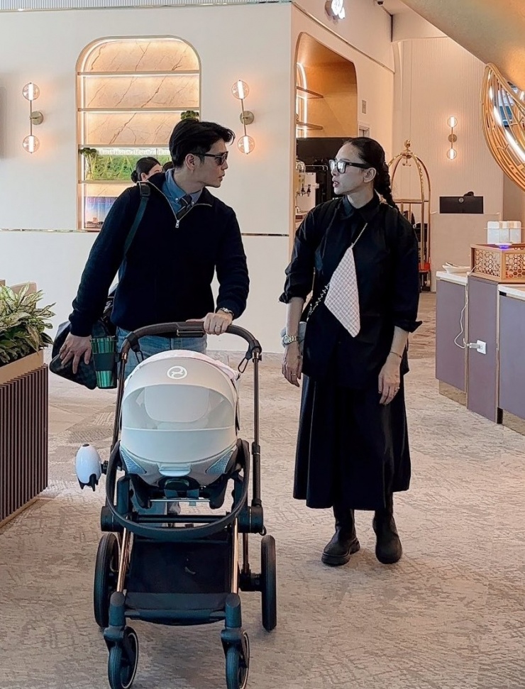 Trong một lần đưa con đi chơi, cô diện cả "cây" đen mang hơi hướng unisex với sơ mi oversized, chân váy midi và bốt chunky. Chiếc khăn sữa của con được cài ở giữa, trở thành điểm nhấn thú vị của tổng thể.