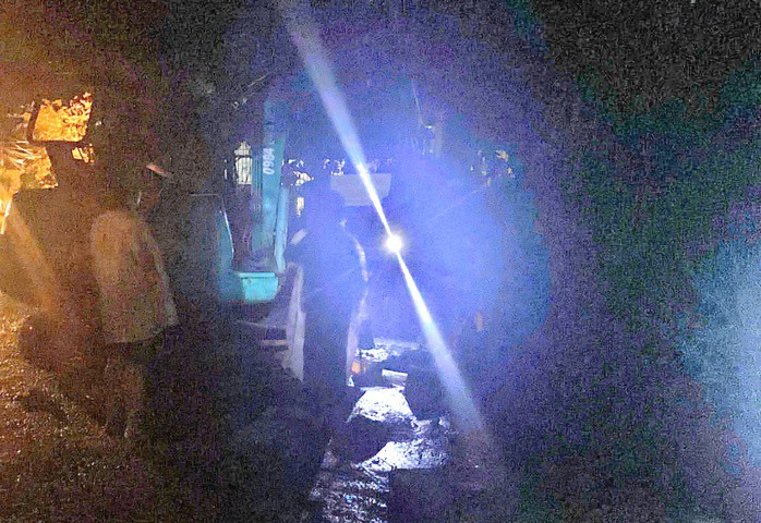 Người dân và lực lượng chức năng dùng máy múc mở nắp cống đưa nạn nhân ra ngoài