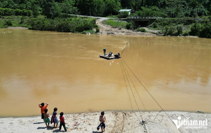 Người dân dùng tay kéo dây cáp để di chuyển chiếc bè trên mặt nước.