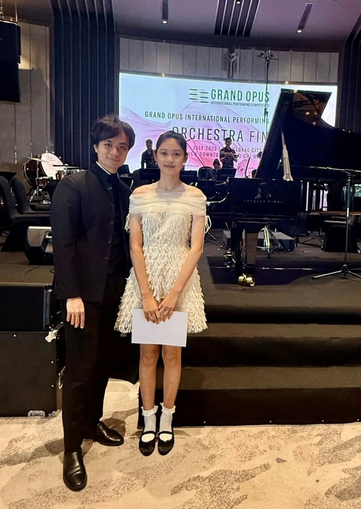 Tiểu Panda bên nhạc trưởng Dustin Tiêu tại buổi trình diễn thuộc cuộc thi Grand Opus Performing Competition - GOPC hồi tháng 7/2025. Anh nhận xét: "Panda học piano không chuyên nhưng có tiếng đàn đẹp. Bé biết thả hồn vào tác phẩm, khả năng cảm nhạc tốt".