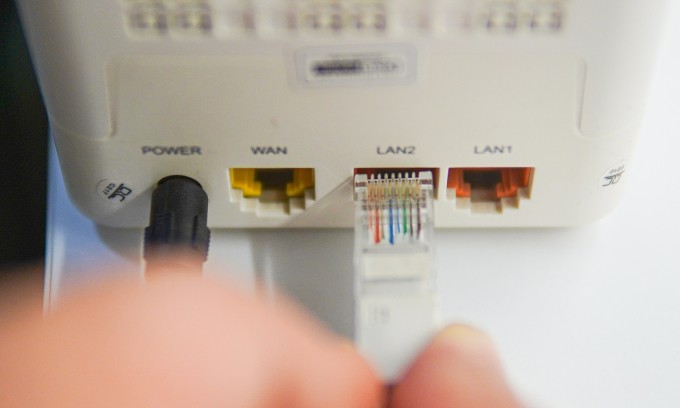 Một người đang cắm dây Ethernet vào modem để kết nối Internet. Ảnh: Lưu Quý