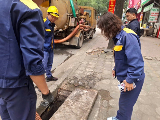 Chị Đức chuẩn bị ghi nhận lại tình hình thực tế của cống thoát nước. Ảnh: Quỳnh Mai.