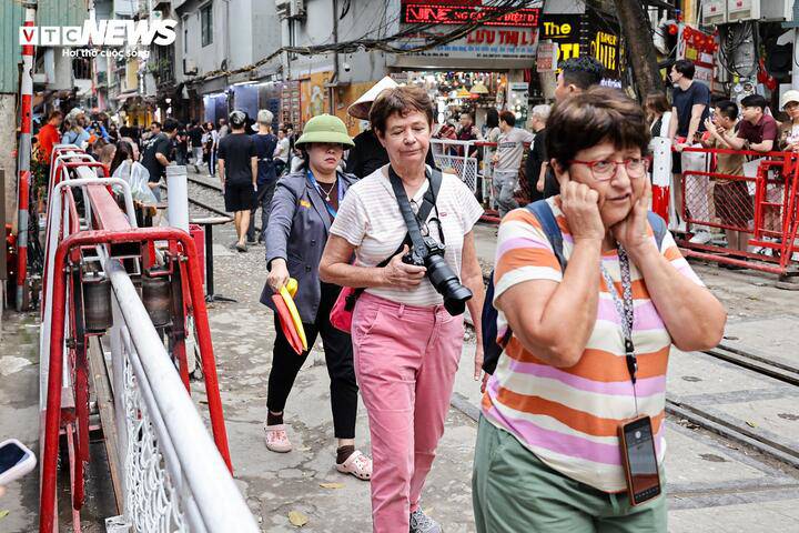 Thậm chí khi tàu chuẩn bị đi qua, nhân viên đường sắt vừa kéo rào chắn, vừa liên tục yêu cầu du khách rời khỏi khu vực nguy hiểm sát đường ray.