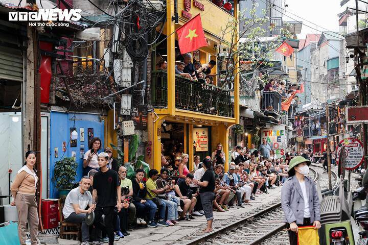 Khi tàu hỏa chạy qua, nhiều du khách ngồi dọc hai bên tuyến đường sắt, chỉ cách đoàn tàu chưa đầy 1m, tiềm ẩn nguy cơ mất an toàn.