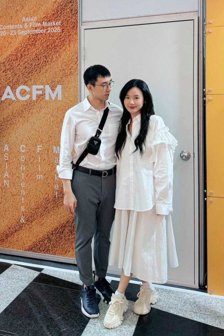 Cặp vợ chồng cùng diện sơ mi trắng và giày thể thao năng động trong một lần công tác Hàn Quốc.