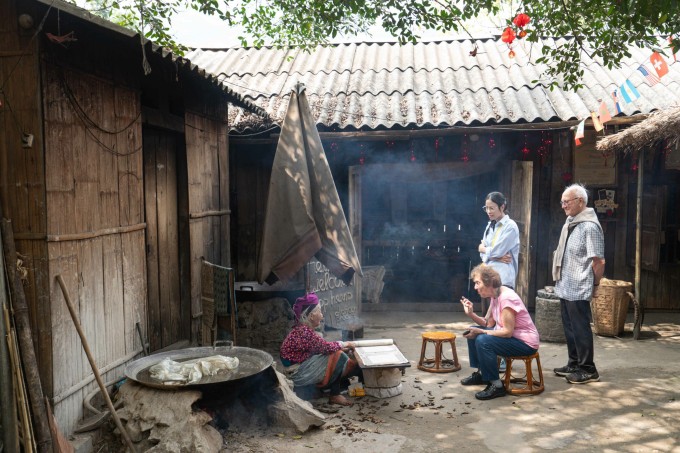 Hai du khách Pháp nghe hướng dẫn viên kể chuyện về cụ Cỏ. Ảnh: Hoàng Giang