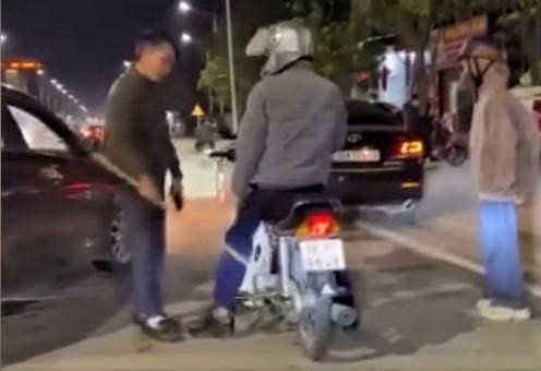 Tài xế dừng ô tô giữa đường và cầm gậy đe dọa người đi xe máy (Ảnh: Cắt từ clip).