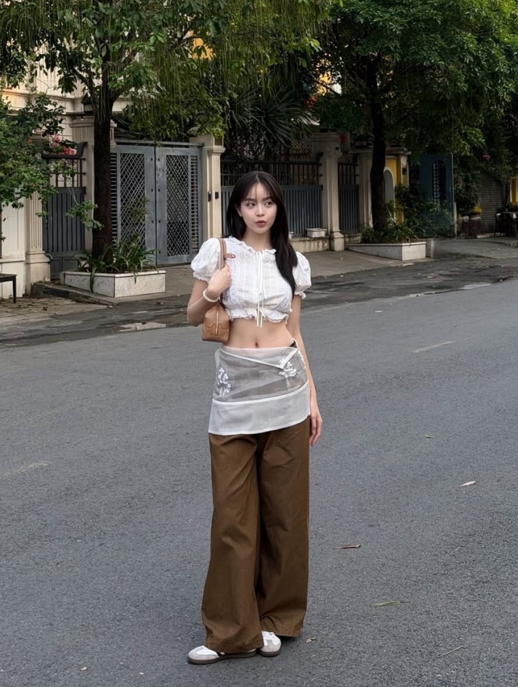 Thanh Thủy dạo phố với bộ cánh gồm crop top, quần suông và sneakers. Trang phục tạo điểm nhấn với khoảng hở, giúp người đẹp khoe vòng eo 63 cm.