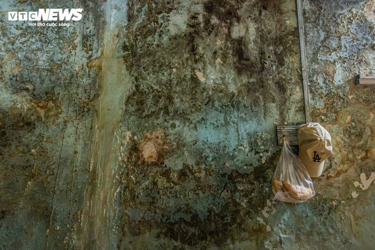 Bức tường ẩm mốc loang lổ trong căn hộ của ông Bảy trở thành nơi treo tạm nhiều vật dụng sinh hoạt mỗi ngày. Ông Bảy cho biết gia đình đã quen với cảnh tường thấm nước, rêu mốc bám đầy nên dần coi đó là chuyện bình thường. “Mình sống lâu thành quen, chứ ai lần đầu nhìn thấy cũng sợ lắm", ông thở dài.