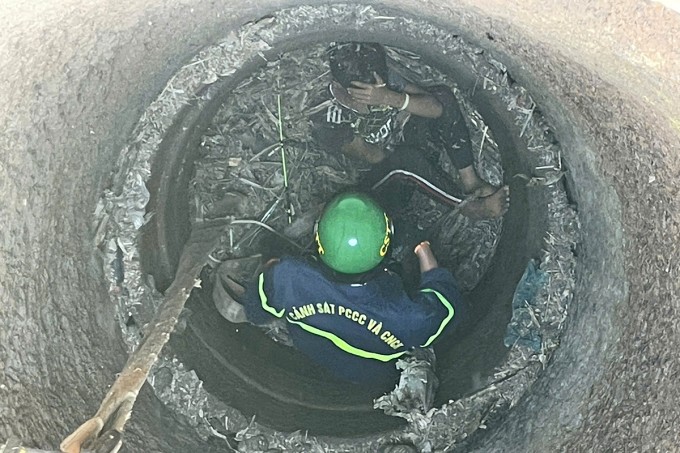 Cảnh sát cứu hộ xuống giếng đưa bé trai lên. Ảnh: Ngọc Oanh