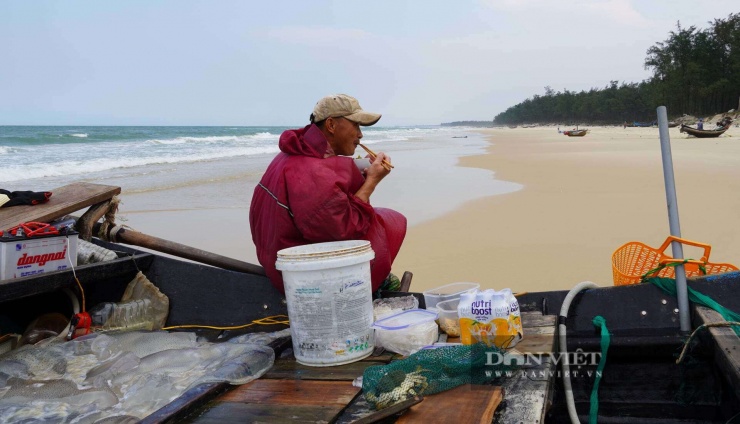 Trong khi những người phụ nữ đưa sứa biển xuống thuyền, những người đàn ông tranh thủ ăn cơm trước khi trở lại đánh bắt. Ảnh: Ngọc Vũ.