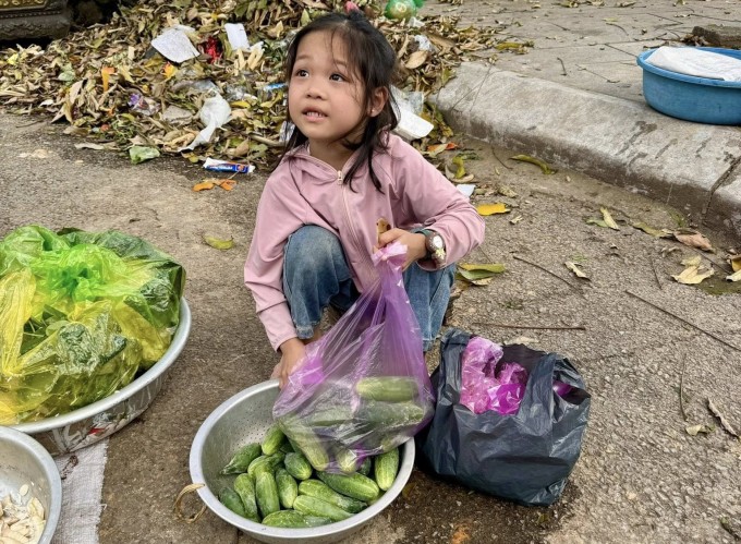 Bé Diệu Anh ra chợ bán rau, phụ bà ở chợ Phố Châu, hôm 17/3. Ảnh: Song Hà