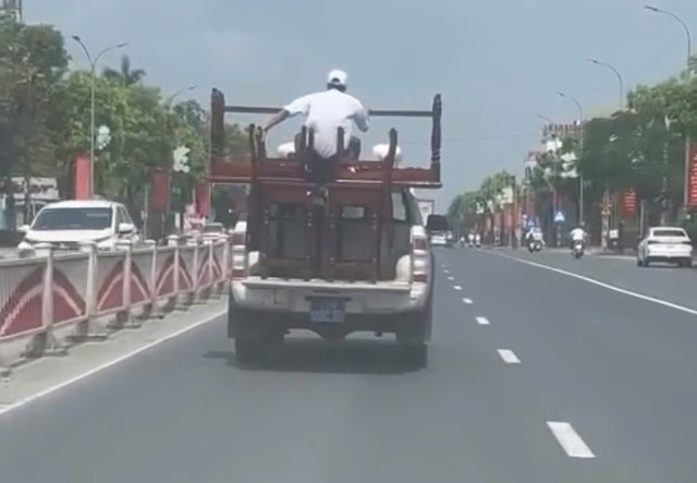 Hình ảnh người đàn ông ngồi trên bàn ghế sau thùng ô tô bán tải. Ảnh cắt từ clip.