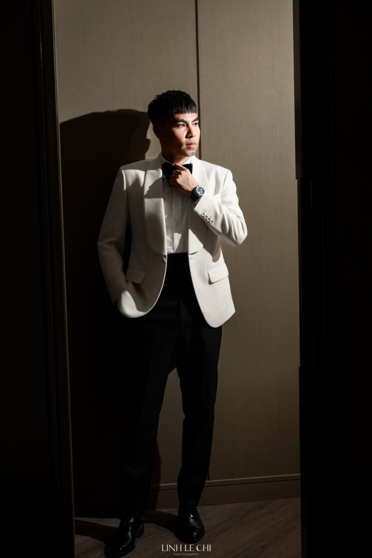 Chiếc tuxedo trông mềm mại nhờ có đường ve áo tạo chiều sâu, đi cùng quần đen, nơ đen trang trọng. Bộ suit tông trắng mang đến vẻ trang nhã cho chú rể Đức Huy trong ngày cưới.