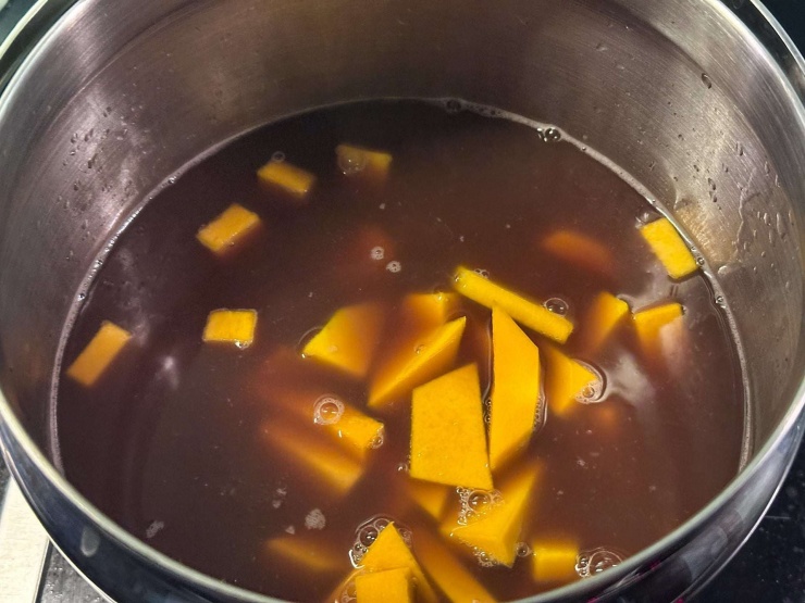 Sau đó cho tiếp gạo nếp và bí đỏ vào đun sôi