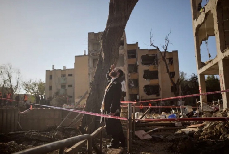 Một người đàn ông đứng trên đống đổ nát của khu nhà trúng tên lửa Iran ở miền nam Israel ngày 22/3. (Ảnh: AP)