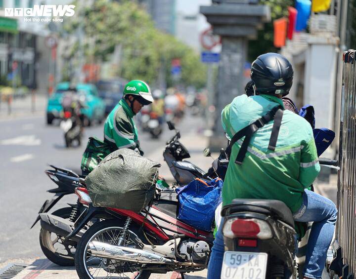 Ông Lâm (bên trái) vừa chạy xe ôm công nghệ vừa tranh thủ nhận đơn giao đồ ăn.