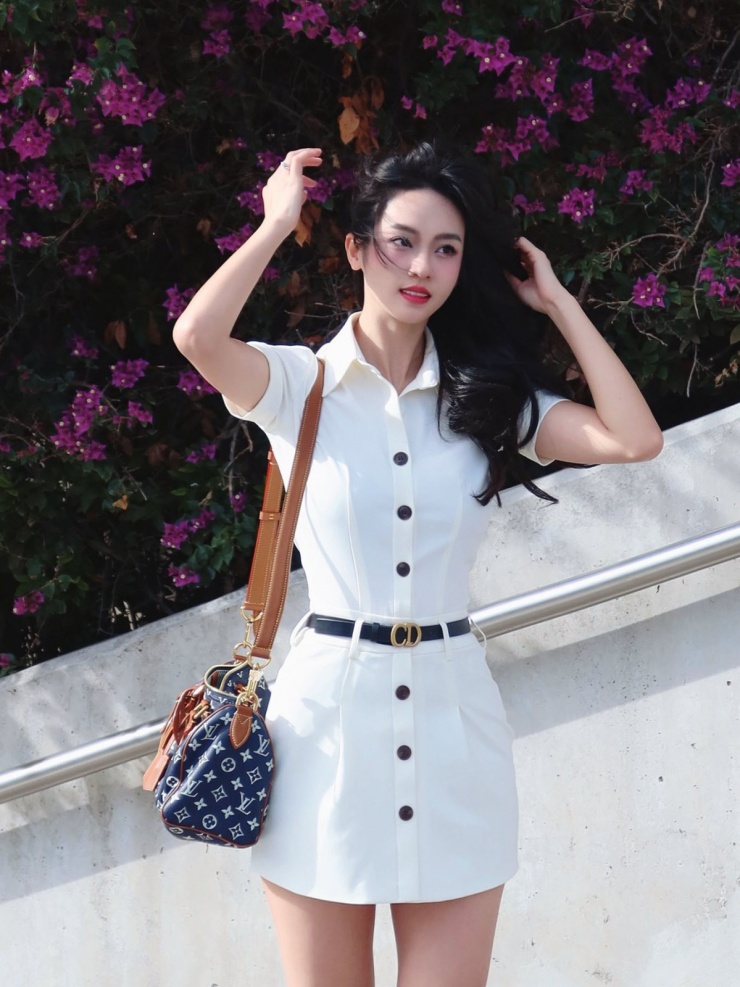 Á hậu Vũ Thúy Quỳnh tạo điểm nhấn cho xiêm y trắng bằng thắt lưng đen Dior và túi xách Louis Vuitton họa tiết monogram.