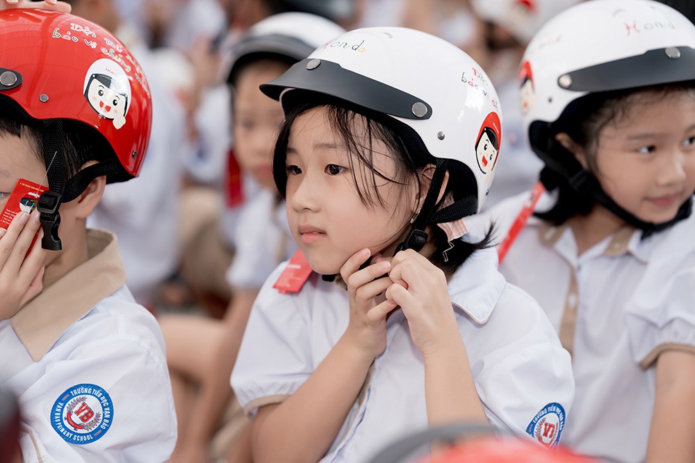 Các em học sinh lớp Một thực hành đội mũ bảo hiểm đúng cách và an toàn