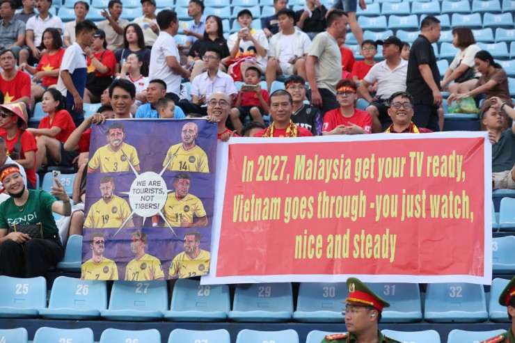 Cổ động viên&nbsp;mang tới sân những tấm băng - rôn với thông điệp hài hước nhưng không kém phần thách thức như&nbsp;"Chúng tôi là khách du lịch, không phải những chú Hổ!" (ảnh trái) hay&nbsp;"Đến năm 2027, Malaysia hãy chuẩn bị sẵn TV đi, Việt Nam sẽ đi tiếp - còn các bạn cứ ngồi đó mà xem, thật bình tĩnh và ổn định nhé" (ảnh phải)