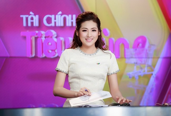 Khi dẫn bản tin Tài chính, Tú Anh chọn trang phục màu sáng, tạo hiệu ứng tương tác với ánh đèn trường quay. Cách trang điểm tươi trẻ và đơn giản.