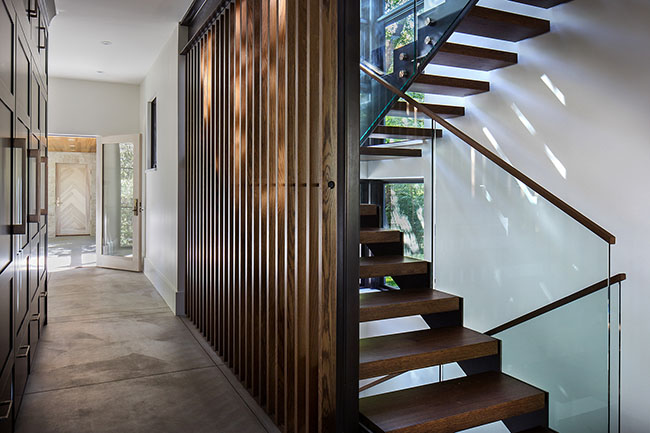 Cầu thang của ngôi nhà được thiết kế bằng gỗ sồi nhuộm đen, nằm kín đáo sau một lớp rèm gỗ.