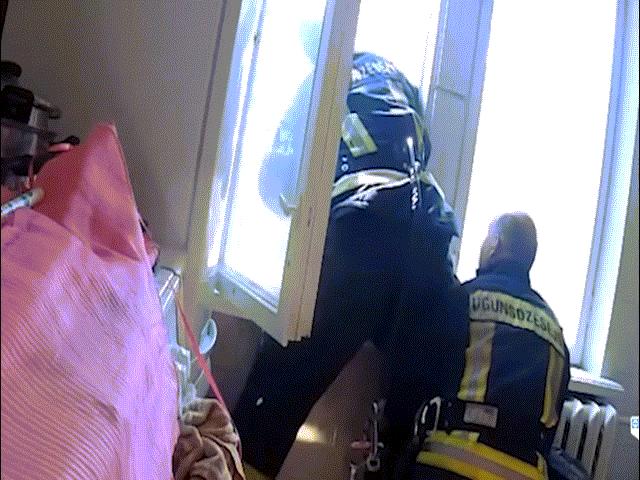 Lính cứu hỏa đứng ở cửa sổ nhoài người giơ tay đỡ người rơi từ trên cao