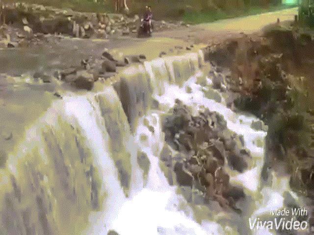 Người dân ”trổ tài” đi xe máy trên đường ”tử thần” trong mưa lũ
