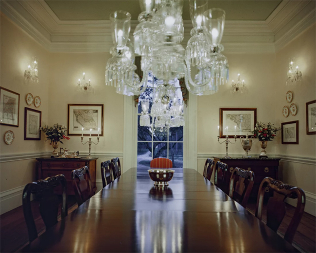 Phòng ăn trang trọng với một chiếc bàn dài đặt cùng đèn chùm pha lê và đèn treo tường lấp lánh.