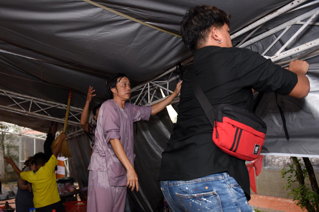 Hoài Linh giản dị, xông xáo giúp đỡ mọi người để có thể lấy các tấm tôn chống dột.