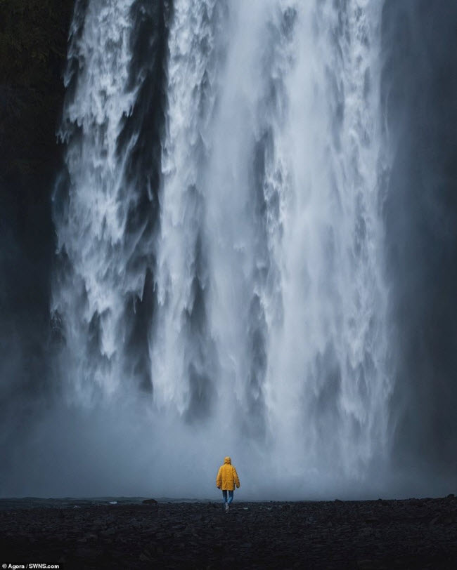 Du khách áo vàng trở nên nhỏ bé khi một mình đứng trước thác Skogafoss ở Iceland.
