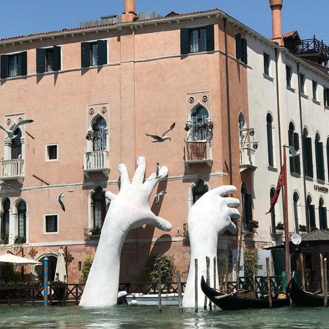 Bàn tay mọc lên từ dòng kênh, như đang cứu lấy thành phố Venice. Đây là tác phẩm của nghệ sĩ Lorenzo Quinn, Venice, Italia.
