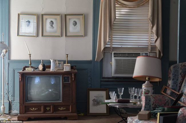Chiếc tivi cũ, những bức ảnh trẻ em, đèn,… vẫn còn nguyên vẹn trong phòng khách của ngôi nhà.
