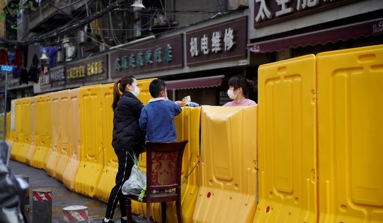 Người phụ nữ Trung Quốc mua rau qua hàng rào ngăn cách ở Vũ Hán.