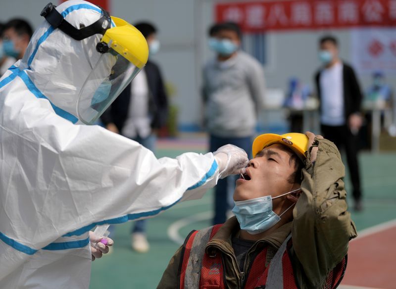 Nhân viên y tế lấy mẫu xét nghiệm Covid-19 cho một công nhân ở thành phố Vũ Hán, tỉnh Hồ Bắc, Trung Quốc hôm 7/4. Ảnh: Reuters