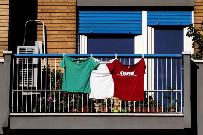 Áo thun mô phỏng màu cờ quốc gia Ý được treo trên ban công một ngôi nhà ở thủ đô Rome (Ý) ngày 16-4. Ảnh: EPA-EFE