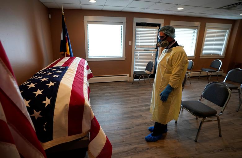 Một nhân viên y tế đứng trước quan tài của một cựu quân nhân Mỹ tử vong vì Covid-19 (ảnh: Reuters)
