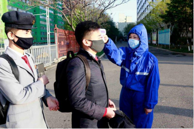 Một sinh viên mang khẩu trang và được
kiểm tra nhiệt độ trước khi vào học lại sau một kỳ nghỉ, tại trường
đại học công nghệ Kim Chaek ở Bình Nhưỡng ngày 22-4. Ảnh: AP