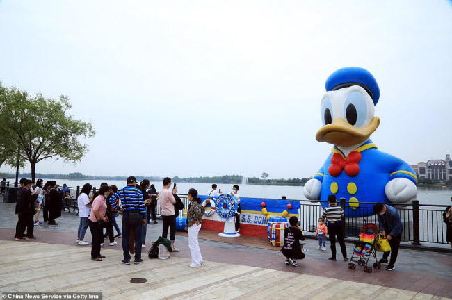 Người dân đeo khẩu trang khi tới khu nghỉ dưỡng và giải trí Disney ở Thượng Hải.