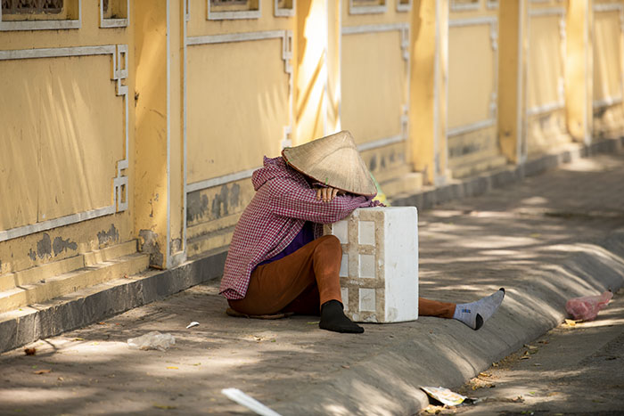 Một phụ nữ bán hàng dưới gốc cây trên đường Hồ Tùng Mậu cũng tranh thủ chợp mắt dưới bóng râm