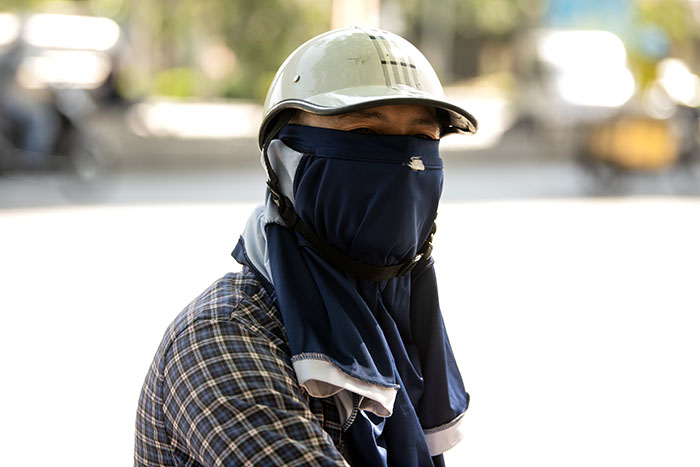 Người dàn ông dùng áo bịt kín mặt để tránh nắng