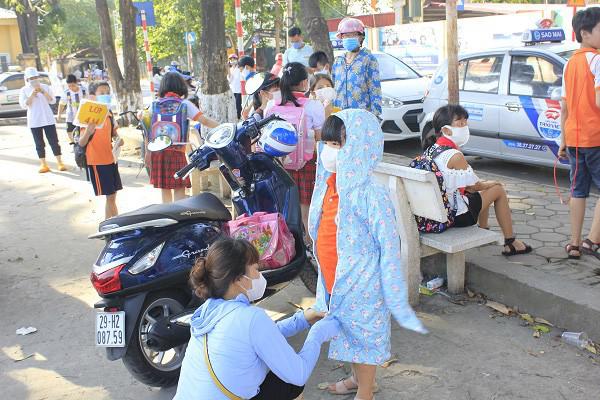 Ra khỏi cổng trường, nhiều học sinh được bao bọc bằng áo chống nắng.