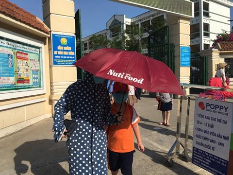 Phụ huynh lẫn học sinh vất vả vì nắng nóng.