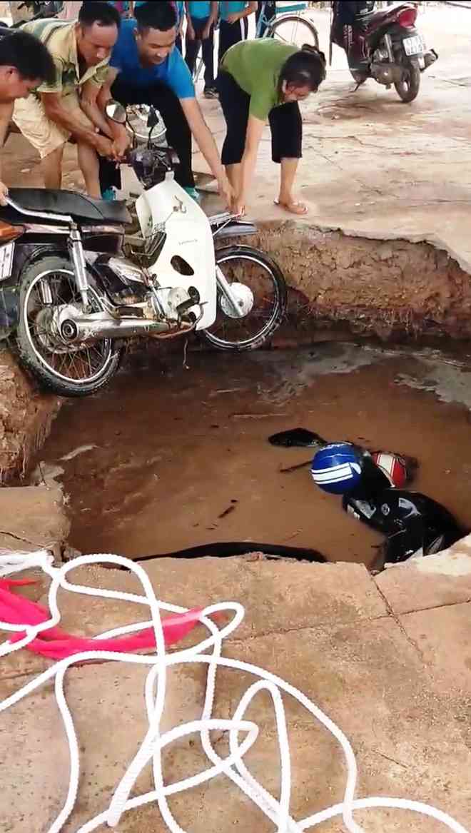 Người dân giúp đưa xe máy bị vùi lấp lên trên