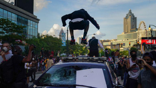 Một người biểu tình nhảy lên xe cảnh sát ở Atlanta. Ảnh: Sky News