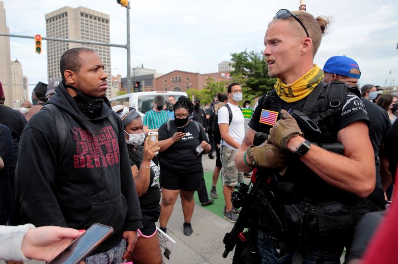 Một thành viên lực lượng đặc biệt (phải) trò chuyện với người biểu tình ở Mỹ. Ảnh: Reuters
