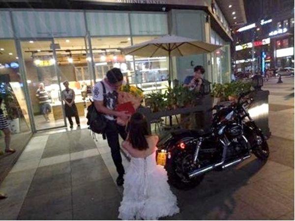 Cô gái mặc váy cưới cầu hôn bạn trai trước một trung tâm thương mại