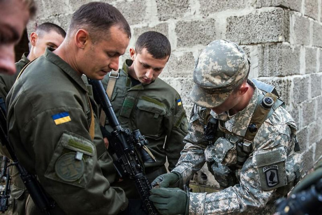 Một sĩ quan quân đội Mỹ (phải) hướng dẫn các binh sĩ Vệ binh quốc gia Ukraine (trái) khi hai nước tập trận chung ở TP Yavoriv hồi tháng 11-2014. Ảnh: AP